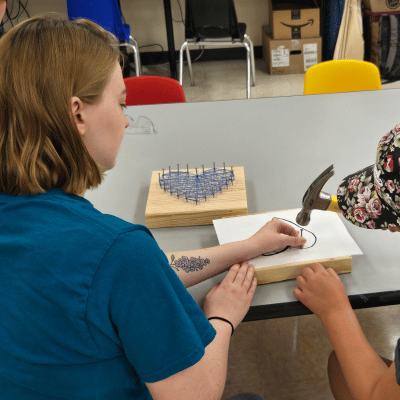 Ali and patron working on a heart design of Nail String Art